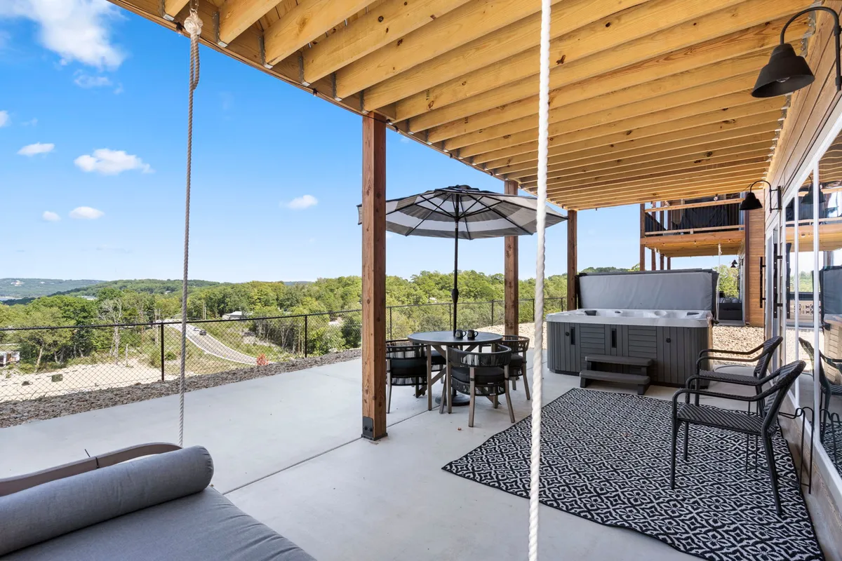 This image features a spacious outdoor deck with a hot tub, dining table, swing chair, and scenic views, offering multiple zones for group relaxation, dining, and play. The setting is ideal for family gatherings or friendly get-togethers, with a sense of openness to the surrounding environment.