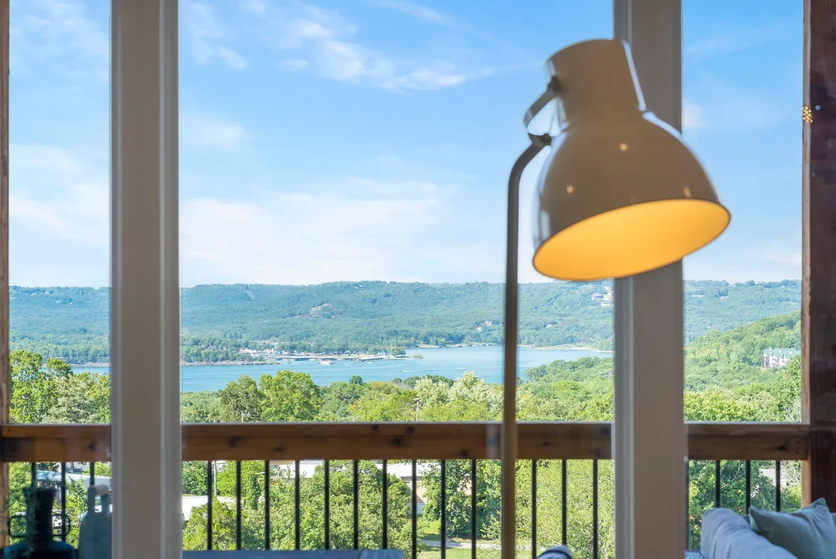 A serene view of the lake framed by lush greenery and a modern lamp, inviting relaxation and reflection. The tranquil atmosphere suggests a peaceful escape where guests can unwind and reconnect with nature after exploring Branson.
