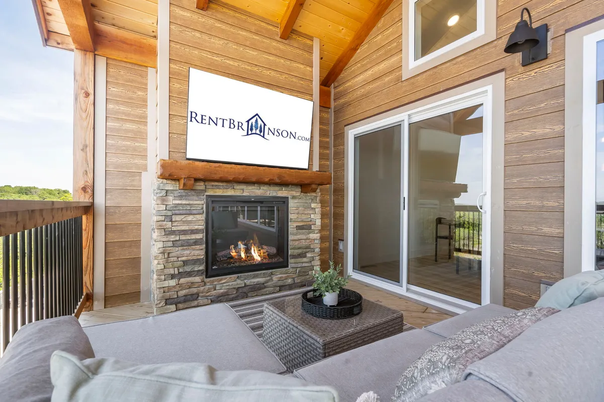 This interior image displays a cozy fireplace, outdoor seating area, and a television screen. The ambiance is warm and modern, perfect for relaxing, watching TV, or hosting a movie night with the backdrop of a sunset outside.