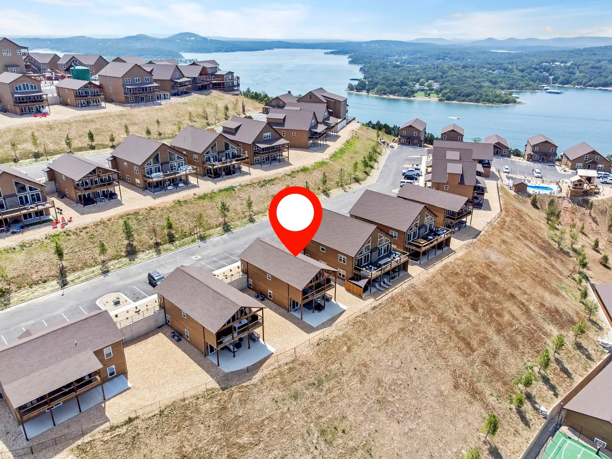A picturesque view featuring a row of houses facing a sparkling lake, with an expansive outdoor space perfect for gatherings. The tranquil water and wide-open sky set a relaxed and celebratory mood ideal for social events.